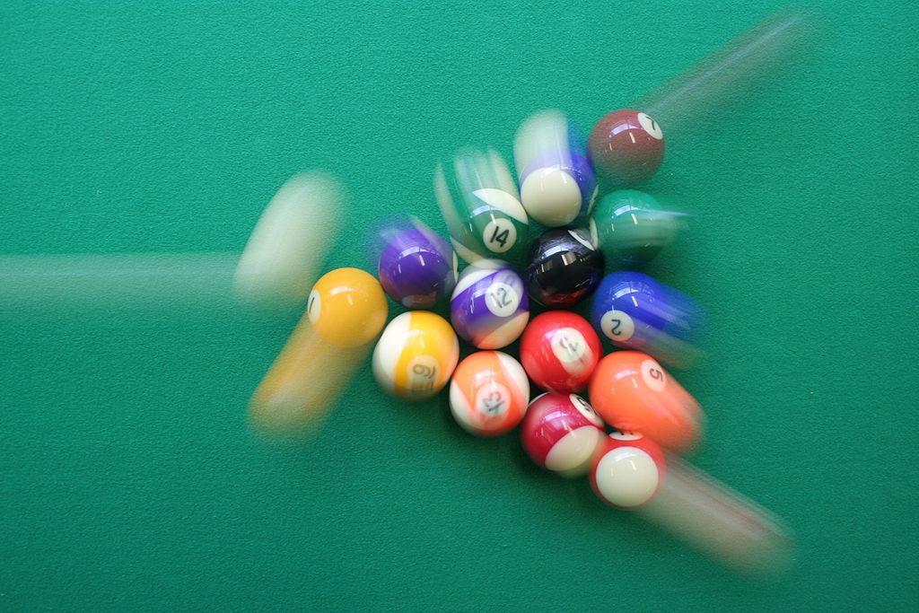 photo showing cue ball breaking a triangle of billard balls