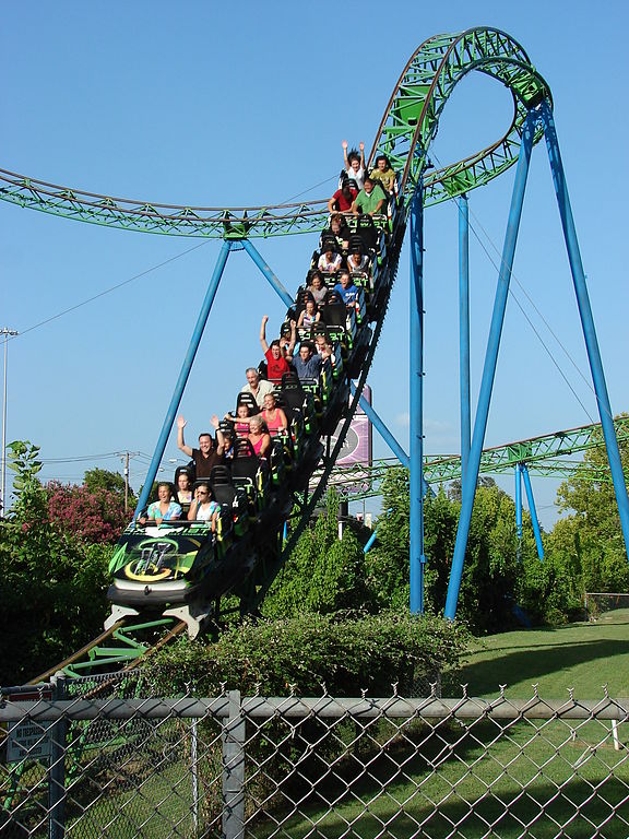 photo showing riders on a roller coaster going down a steep hill